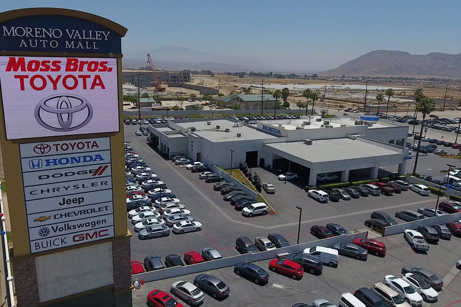 Aerial view of Moreno Valley Auto Mall showcasing various dealerships, including Toyota, Honda, Dodge, Chrysler, Jeep, Chevrolet, Volkswagen, Buick, and GMC, with numerous parked vehicles.