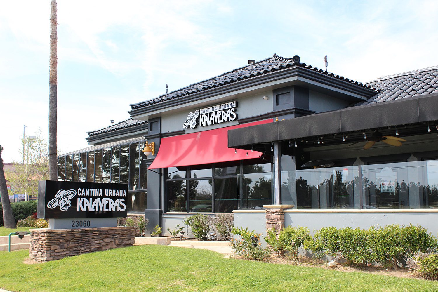 Exterior of Cantina Urbana Klaveras, a restaurant with a modern design, red awning, and signage at the entrance, located at 23060.